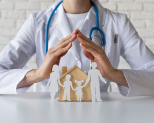 Manos de un profesional médico protegen figuras de una familia y una casa
